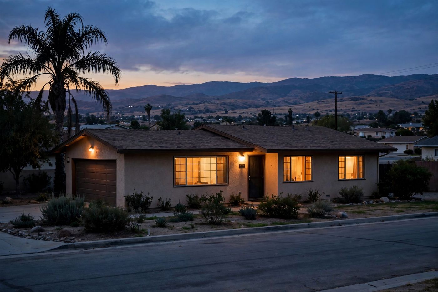 A Bakersfield home at dusk with its windows glowing warm